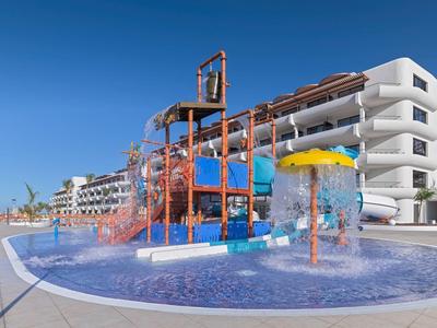 Venkovní vodní park s tobogány a stříkacími prvky u hotelu pod jasnou modrou oblohou