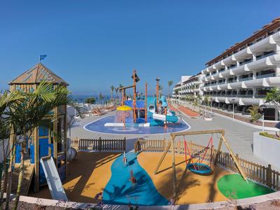 Hotel s venkovním hřištěm a barevným vodním hřištěm pod jasnou modrou oblohou