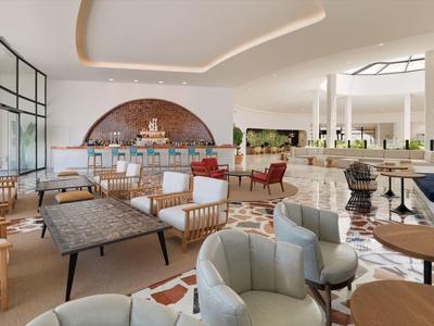 Prostorná hotelová lobby s moderním nábytkem, velkými okny a neutrálními tóny.