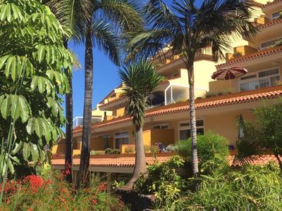 Hotel s tropickými rostlinami a palmami pod jasně modrou oblohou