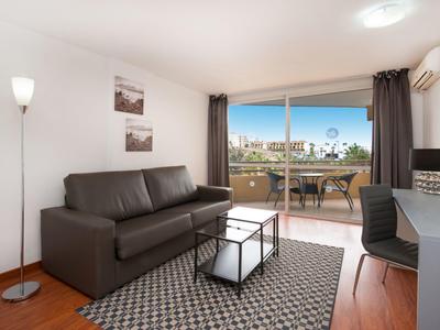 Soggiorno moderno con divano marrone, tappeto e balcone con vista.