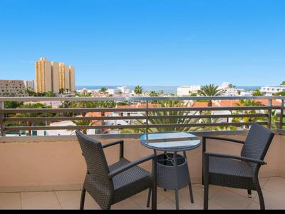 Balcone con due sedie e un piccolo tavolo con vista sulla città e cielo azzurro.