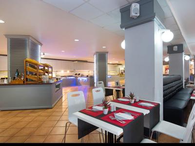 Moderner Frühstücksraum mit gedeckten Tischen und Buffet im Hintergrund.