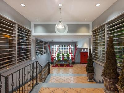 Ingresso moderno con finestre in vetro, illuminazione elegante e piante decorative.