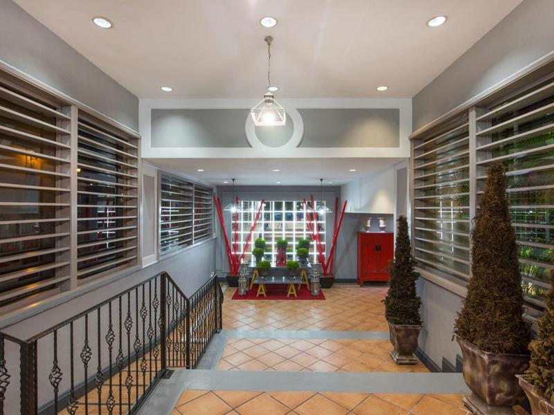 Ingresso moderno con finestre in vetro, illuminazione elegante e piante decorative.