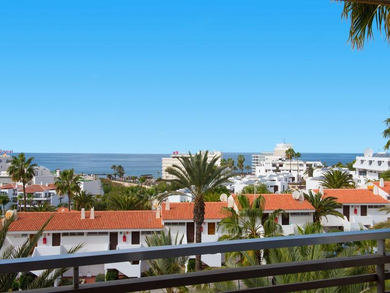 Vista di case mediterranee con tetti rossi e palme vicino al mare