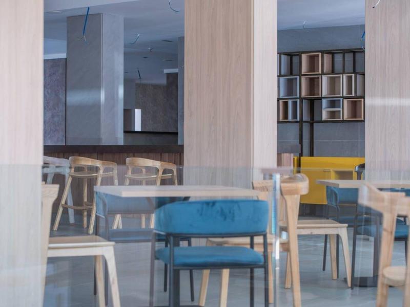 Modern, rustig interieur met meerdere houten stoelen en een blauwe stoel op de voorgrond.