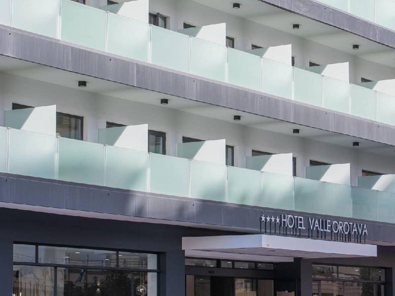 Moderne hotelbalkon met heldere glazen balustrades en meerdere verdiepingen bij daglicht.