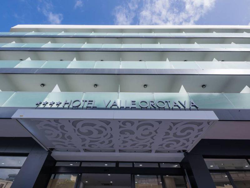 Modern meerlaags hotelgebouw met versierde ingang en blauwe lucht op de achtergrond.