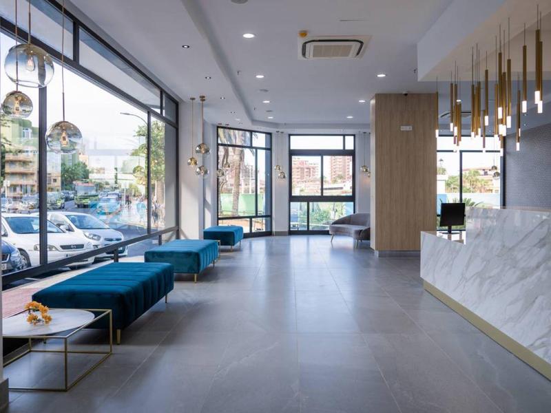 Lichte, moderne hotel lobby met banken, grote ramen en stijlvolle receptie.