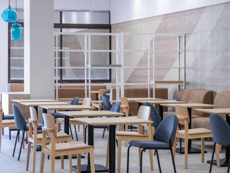 Moderne hotel- of restaurantruimte met houten en beklede stoelen en tafels.