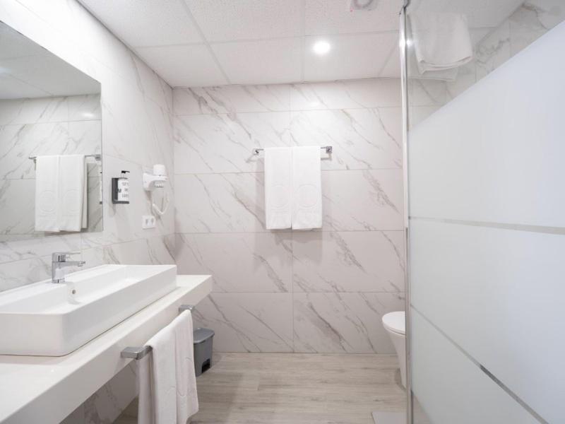 Moderne badkamer met wastafel, handdoeken en doucheruimte met matglaswand.