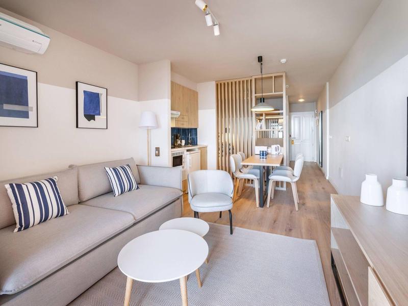 Moderní obývací pokoj s béžovou pohovkou, bílým křeslem a kulatým stolkem.