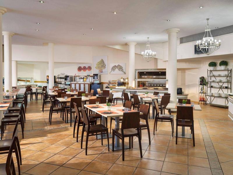 Velká světlá jídelna s dřevěnými stoly a židlemi v hotelu.