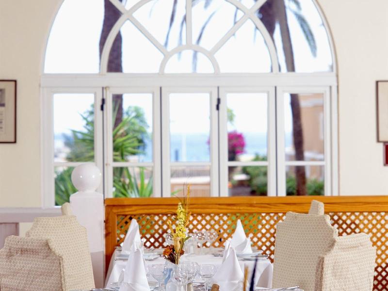 Elegantní jídelna s výhledem na moře přes velké obloukové okno.