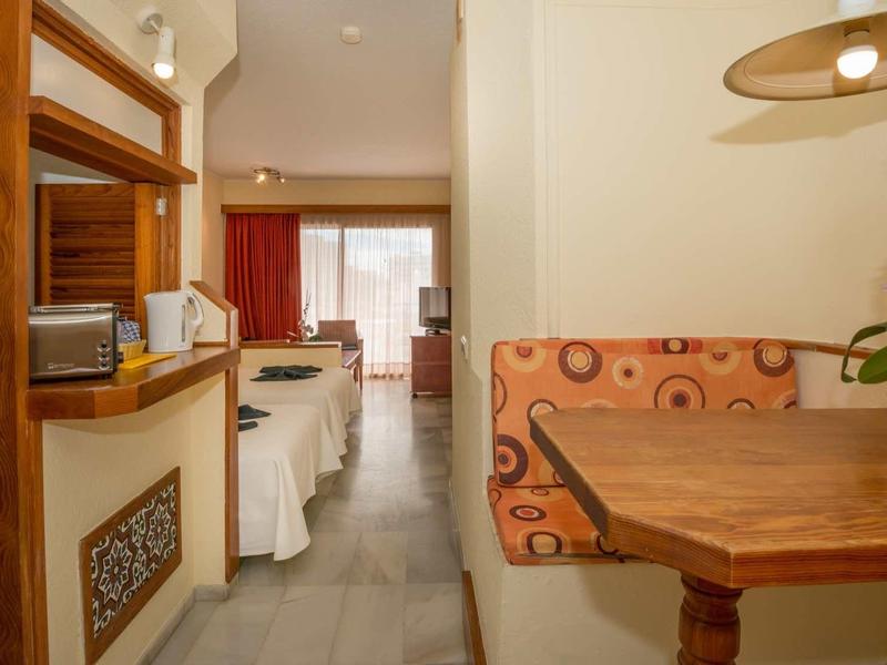 Cozy dining area with wooden table and cushioned bench, connected to living space with large windows.