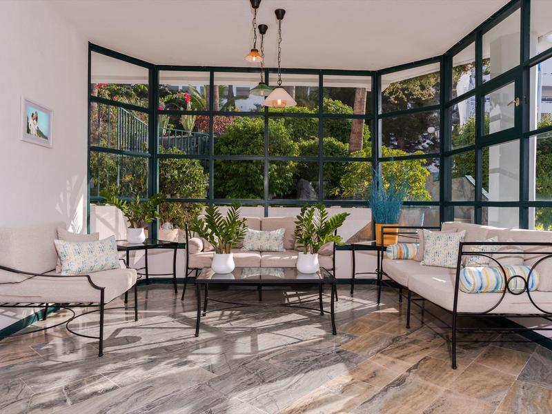 Jasny ogród zimowy z wygodnymi miejscami do siedzenia i dużymi oknami z widokiem na zieleń