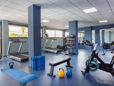 Palestra moderna con attrezzi da allenamento e grande parete a specchio in stanza luminosa.