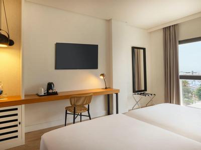 Modernes Hotelzimmer mit Schreibtisch, Stuhl, TV und großem Fenster mit Aussicht.