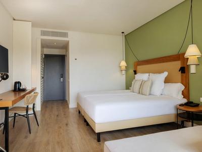 Modernes Hotelzimmer mit Doppelbett, Schreibtisch und grüner Akzentwand.