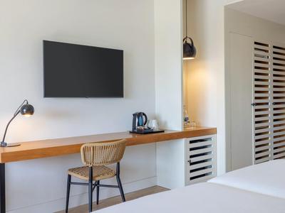 Moderner Hotelzimmerarbeitsbereich mit Wandfernseher, Schreibtischlampe und Stuhl.