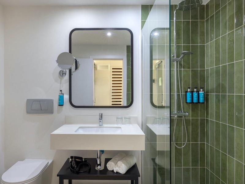 Modernes Badezimmer mit grün gefliestem Duschbereich, Waschtisch und Spiegel