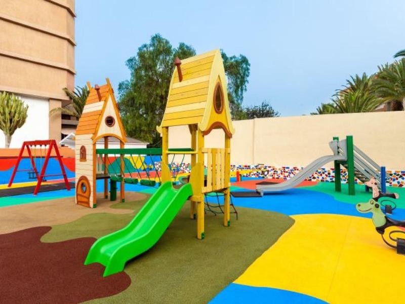 Bunter Kinderspielplatz mit Rutschen, Schaukeln und Klettergerüsten auf weichem Boden.