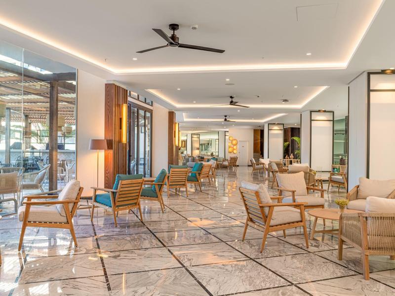 Espace lounge d'hôtel lumineux et spacieux avec mobilier moderne et sol en marbre.