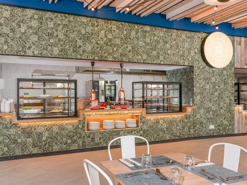 Restaurant moderne avec fenêtre de cuisine ouverte et mur vert.