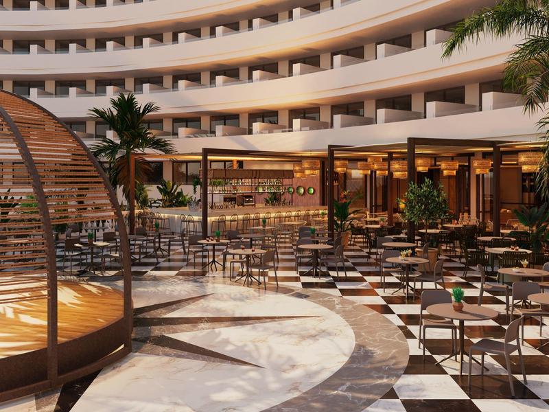 Grand patio d'hôtel moderne avec bar, sièges et palmiers.