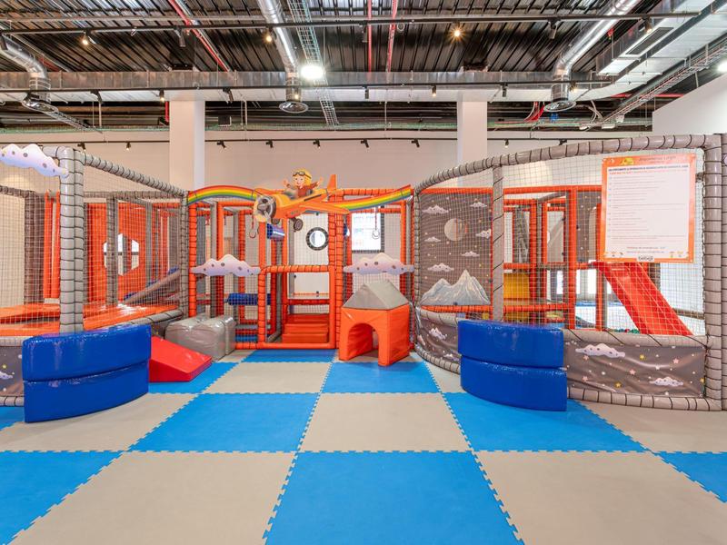 Aire de jeux intérieure pour enfants avec sol coloré et structures d'escalade