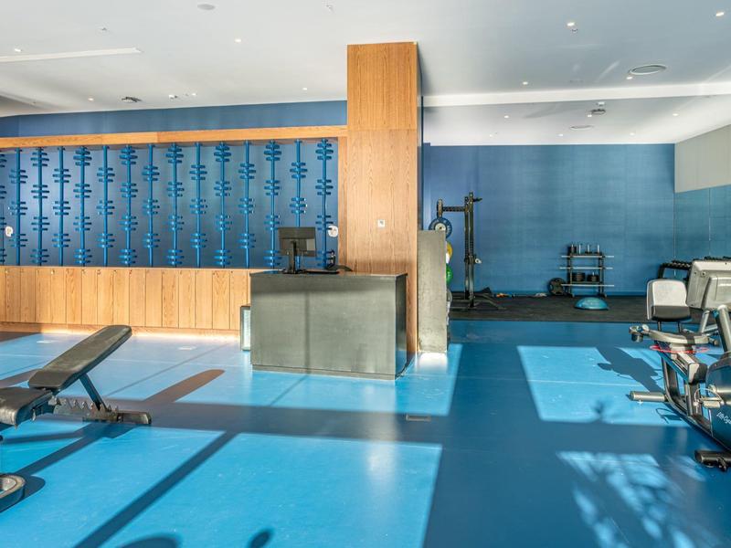 Salle de sport moderne avec sol bleu et panneaux en bois sur les murs.
