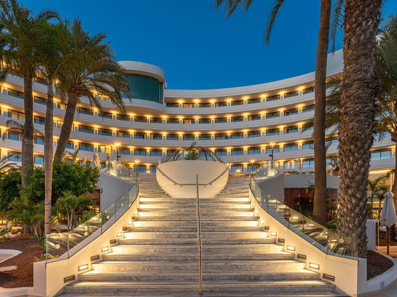 Escalier illuminé menant à un hôtel moderne avec balcons la nuit.