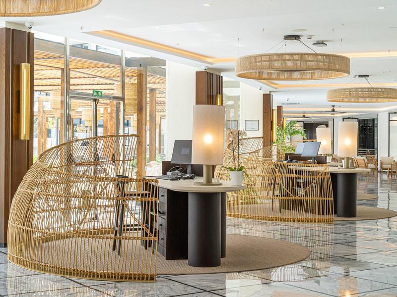 Restaurant d'hôtel moderne avec chaise en bambou, sol en marbre et éclairage chaleureux.