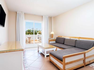 Salon moderne avec canapé, télévision et balcon donnant sur la mer.