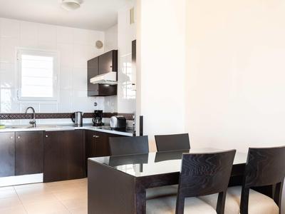 Salle à manger moderne avec table noire et chaises près d'une cuisine ouverte.