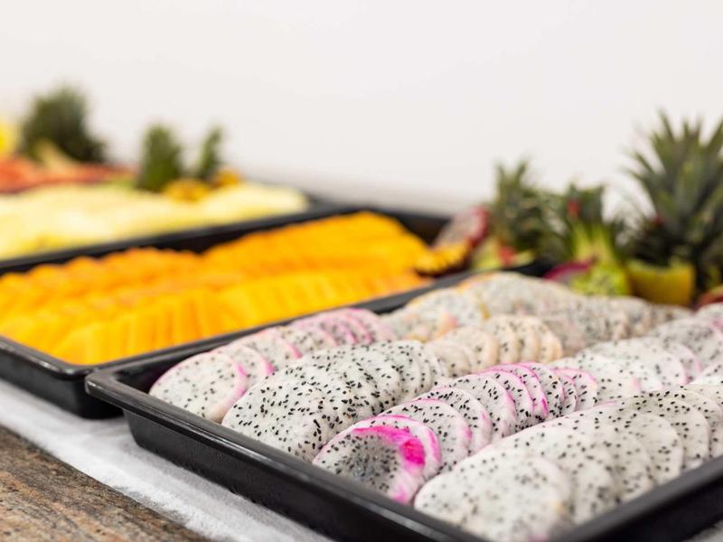 Gros plan de différentes fruits tropicaux tranchés sur des plateaux dans un buffet.