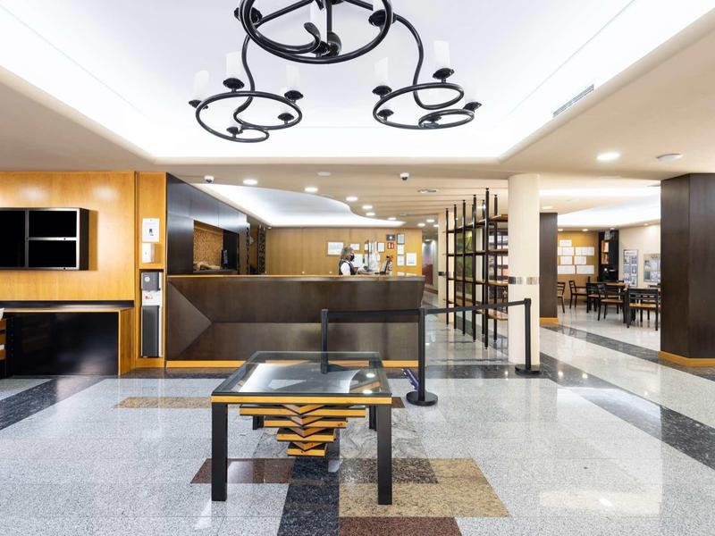 Hall d'hôtel moderne avec mobilier minimaliste et éclairage au plafond distinctif.