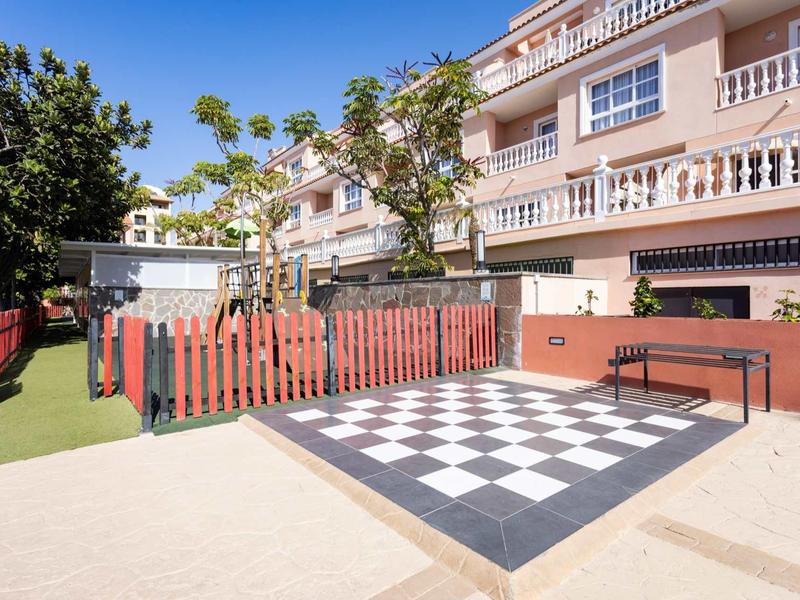 Cour intérieure avec motif d'échiquier, clôture et banc à côté d'un immeuble à plusieurs étages.