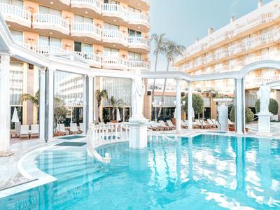 Moderner Hotelpool mit weißen Säulen, blauen Wasser und mehrstöckigem Gebäude im Hintergrund.