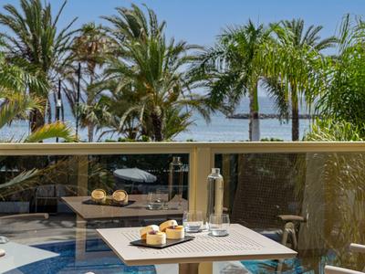 Tavolo sul balcone con bevande e spuntini, circondato da palme e vista piscina