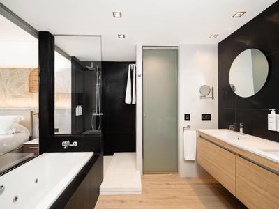 Modern hotelbadkamer met bad, douche en houten meubels.