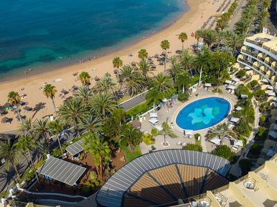 Luchtfoto van hotelzwembad, palmbomen en strand met blauwe zee.