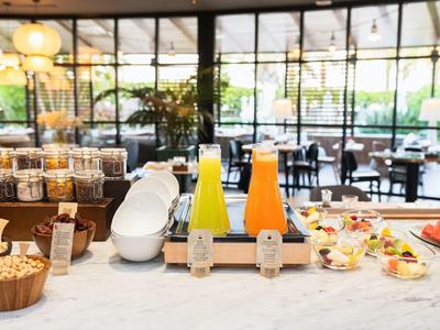 Ontbijtbalie met sapdispensers, granen en yoghurtbekers in een lichte eetruimte.