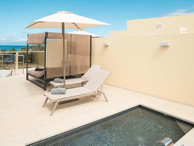 Terras met ligstoelen, parasol, klein zwembad en uitzicht op zee.