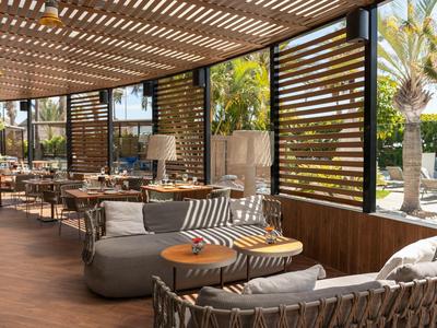 Gemütliche Sitzbereiche unter einem überdachten Außenbereich mit Holzboden und Sichtschutz.