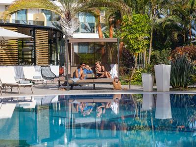 Due persone si rilassano accanto a una piscina dell'hotel con ombrelloni e lettini