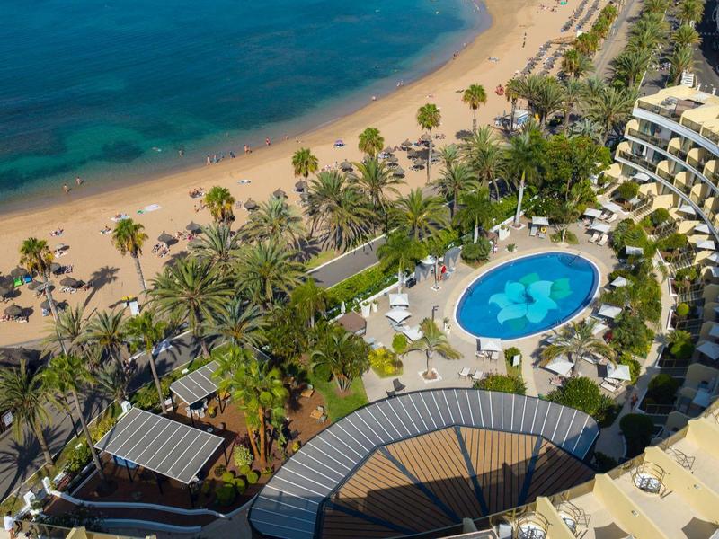 Luchtfoto van hotelzwembad, palmbomen en strand met blauwe zee.
