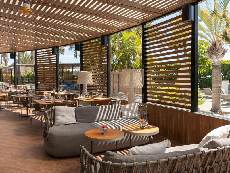 Gezellige zitplekken onder een overdekte buitenruimte met houten vloer en privacy schermen.