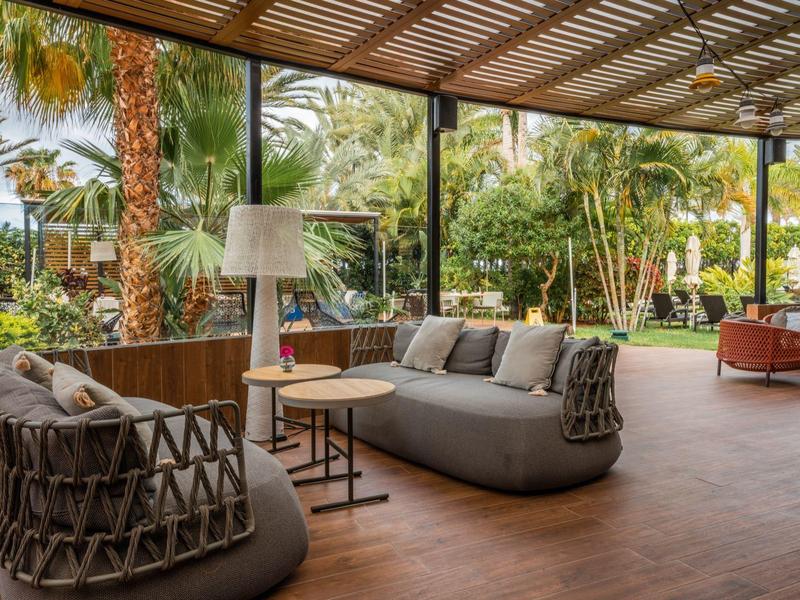 Moderne buitenzitplaats met comfortabele meubels en uitzicht op een tuin.